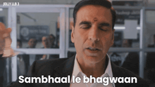 a man in a suit and white shirt is saying sambhaale bhagawaan