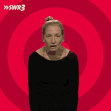 a woman in a black shirt stands in front of a red circle with swr3 on it