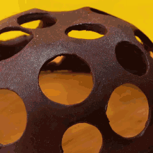 a close up of a sphere with holes in it on a yellow background