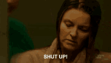 a woman is holding another woman 's face and the word shut is being displayed .