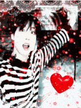 a boy in a black and white striped shirt with a red heart in the background