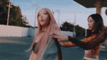 two women with pink hair are standing next to each other