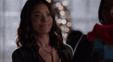 a woman wearing a black jacket and a necklace smiles