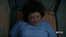 a woman in a blue shirt is laying on a wooden table with netflix written on the bottom