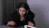 a woman wearing headphones is sitting at a desk in front of a computer screen .