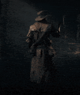 a man wearing a cowboy hat and a trench coat is standing in the dark