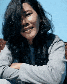 a woman with her arms crossed is smiling and looking at the camera