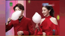 a man and a woman are eating cotton candy on a red background .