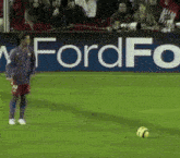 a soccer player in front of a ford advertisement