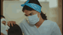 a woman wearing a bandana and a face mask looks at another woman