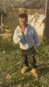 a man wearing a nike hoodie stands in a grassy field