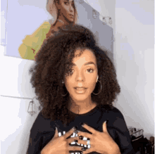 a woman with curly hair wearing hoop earrings and a black shirt