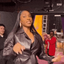 a woman in a leather jacket is dancing in front of a mirror .
