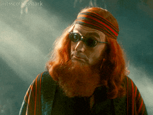 a man with red hair and a beard is wearing sunglasses and a striped headband