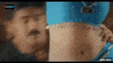 a man is touching a woman 's stomach in a blue top .