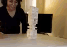 a woman in a black shirt is playing jenga