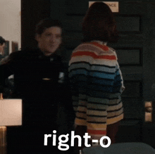 a woman in a striped sweater is standing next to a man in a black shirt with the word right-o on it