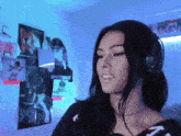 a woman wearing headphones is standing in front of a wall with posters on it