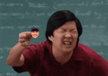 a man in a red shirt is pointing at a small picture of a man 's face