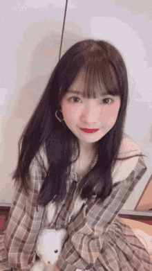 a girl in a plaid shirt holds a teddy bear in her lap