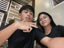 a boy and a girl are posing for a picture and the girl is wearing glasses
