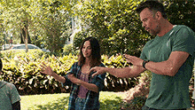 a man in a green shirt is standing next to a woman in a plaid shirt .