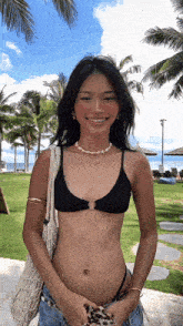 a woman in a bikini is smiling and holding a bag