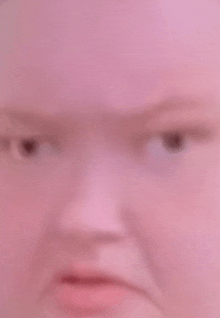 a close up of a person 's face with a pink background and a blurred background .