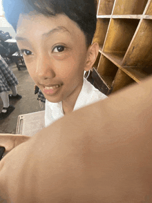 a young boy sitting at a desk in a classroom with a shelf in the background