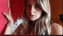 a woman with a tattoo on her wrist has a tear running down her eye