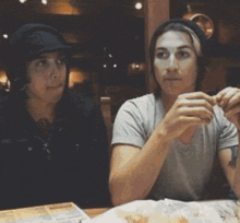 two people are sitting at a table and one of them is wearing a hat that says ' a ' on it