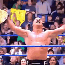 a man is standing in a wrestling ring with his arms outstretched holding a championship belt .