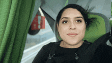a woman is sitting in a green seat with a seat belt on