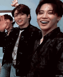 a group of young men are standing next to each other smiling and waving their hands .