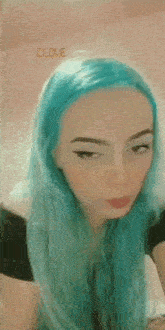 a woman with blue hair is making a funny face and looking at the camera .