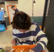 a woman in a striped sweater is eating pizza
