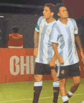 two soccer players are standing in front of a red wall that says chi