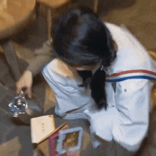 a woman in a white jacket is sitting at a table with a book and a cell phone