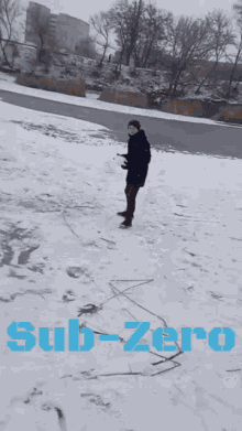 a man standing in the snow with the word sub-zero written in blue