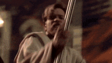a man in a robe is holding a pole in his hand and making a funny face .