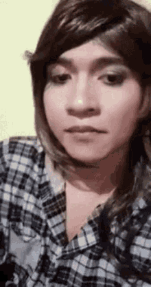 a close up of a person wearing a plaid shirt and wig .