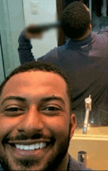 a man is smiling in front of a mirror while brushing his hair