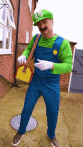 a man dressed in a luigi costume holds a yellow box
