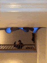 a person is standing on a balcony looking down at a blue light