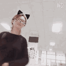 a woman wearing glasses and cat ears is dancing in a room with a white ceiling .