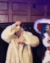 a woman in a fur coat is dancing with another woman in a santa costume
