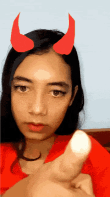 a girl with devil horns on her head pointing at the camera
