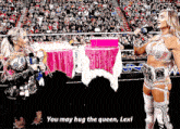 a woman in a wrestling ring says " you may hug the queen " to another woman