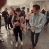 a man and a woman are walking in a crowded room .