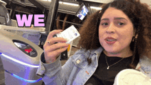 a woman is holding a ticket in front of a machine that says we
